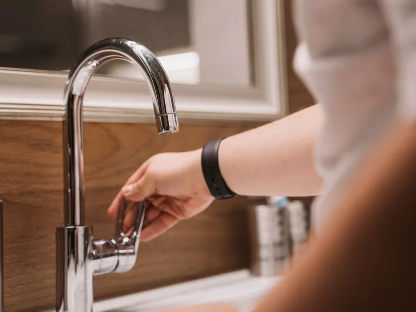 Main qui ferme un robinet d’eau